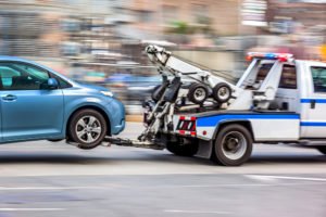 A police tow truck towing away a car after a DUI arrest and taking it to an impoundment lot.