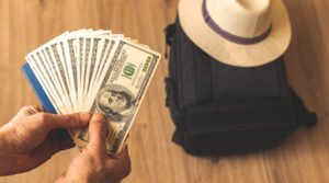 Dinero de viaje junto a una maleta y un sombrero de sol Dinero de viaje junto a una maleta y un sombrero de sol