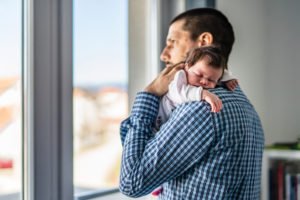 Padre nuevo sosteniendo recién nacido mientras está en licencia FMLA