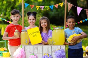 A group of children selling lemonade at their lemonade stand.