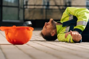 Trabajador de construcción en el suelo con lesión en el brazo