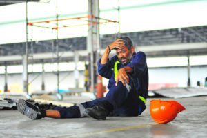 Construction worker on ground after fall accident with scaffolding in background