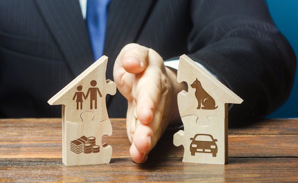 Man's hand dividing a house in half, signfying divorce