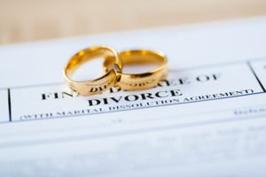 Divorce papers with two wedding rings on top