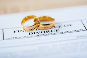 Papeles de divorcio con dos anillos de boda encima