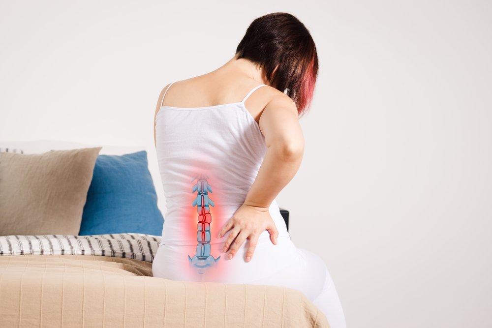 Una mujer que experimenta dolor de espalda debido a la enfermedad de disco degenerativo.