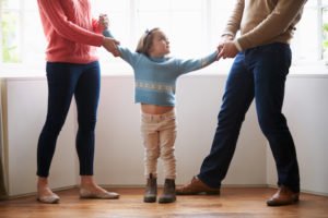 Two parents holding a child by each arm