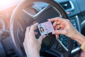 Dos manos sosteniendo una licencia de conducir contra un volante
