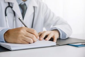 A doctor writing his patient a note to provide to his employer.