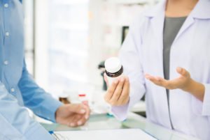 Farmacéutico entregando una botella de medicamentos a un cliente en una farmacia