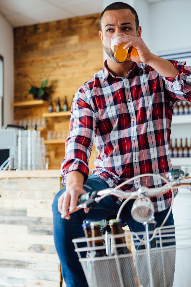A man chugging a beer just as he is about to go on a bike ride.