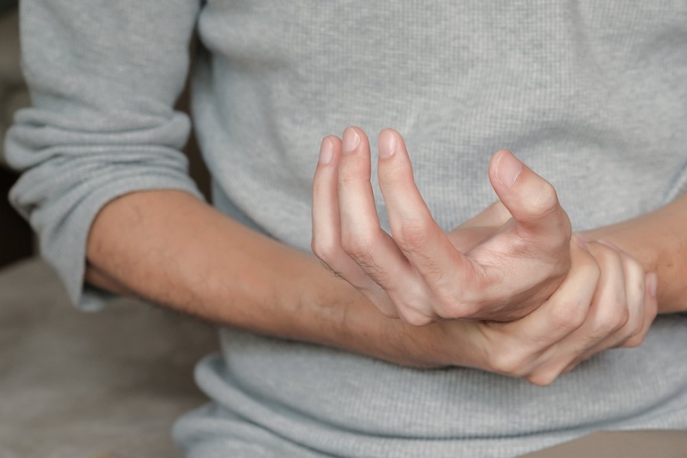 A person holding his hand in pain, due to nerve damage after an injury.