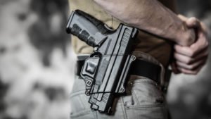 Close-up de una pistola descargada siendo llevada abiertamente en la cintura de un hombre