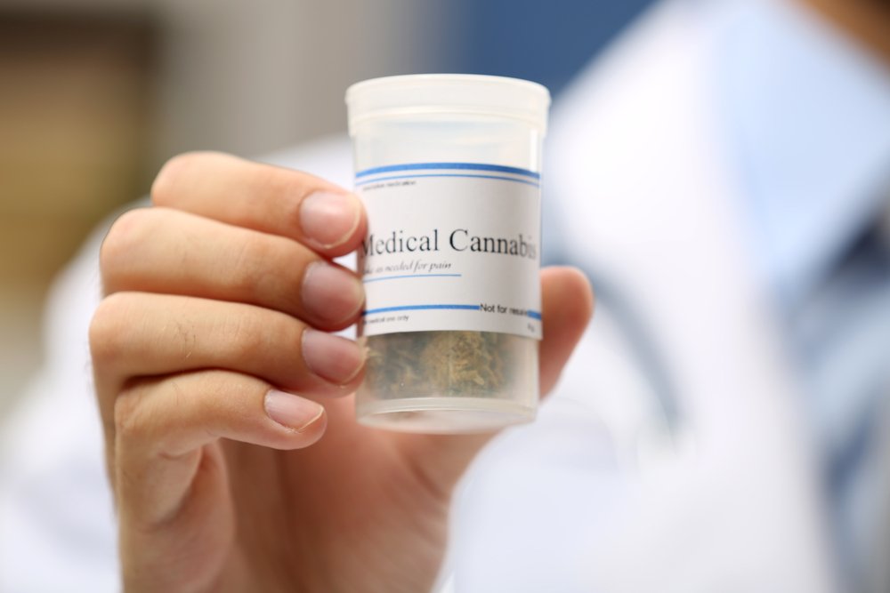 Una persona con una bata de laboratorio sosteniendo cannabis médica.
