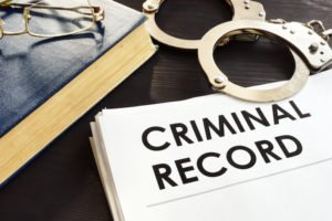 Paper that says "criminal record" next to handcuffs