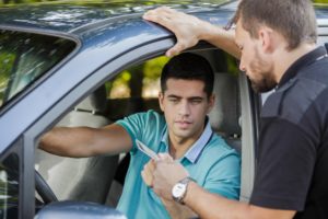 A man handing a police officer a possibly suspended or revoked driver's license.