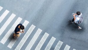 Birds-eye view of people crossing on crosswalk and outside of crosswalk