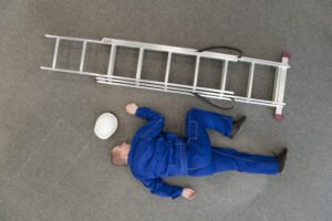 Worker on ground with ladder after fall from roof
