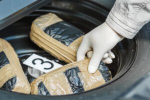 Un agente del gobierno tamizando bolsas de drogas almacenadas en el área de la rueda de repuesto de un vehículo.