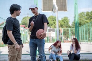 Un adolescente mostrando un cigarrillo de marihuana (un joint) a un menor, potencialmente con la intención de venderlo.