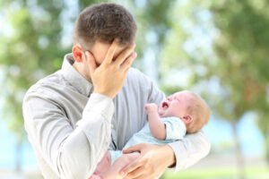 Frustrated father holding a crying baby