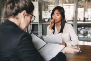 Solicitante de empleo nervioso durante una entrevista de trabajo mientras el entrevistador revisa su verificación de antecedentes Solicitante de empleo nervioso durante una entrevista de trabajo mientras el entrevistador revisa su verificación de antecedentes