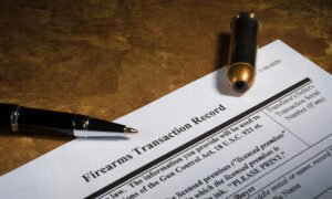 Paper that says "firearm transaction record" with a pen and bullet cartridge