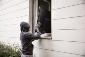 Burglar carrying television out through a window