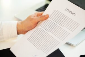 Hand holding a paper that says contract