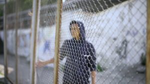 Juvenile in a hoodie behind a gate