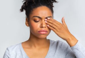 Woman in pain rubbing her sore eye 