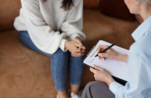 Psychologist with a clipboard speaking with a patient