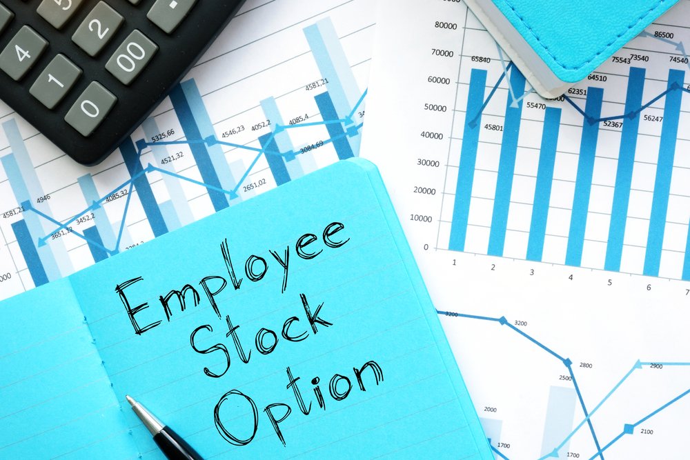 A note saying "Employee Stock Option" sits atop financial charts, next to a calculator.