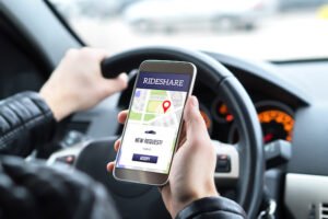 Conductor de Uber revisando la aplicación en el teléfono mientras conduce