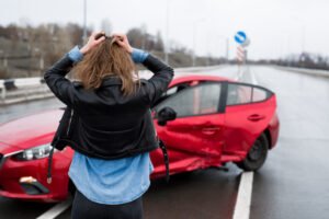 Woman standing in front of car after a sideswipe accident.