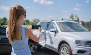 Mujer fotografiando daños en el auto después de un accidente