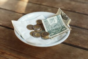 Dish with coins and dollars as tips