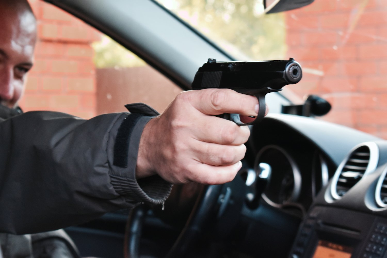 Man shooting gun from the driver's seat of a car