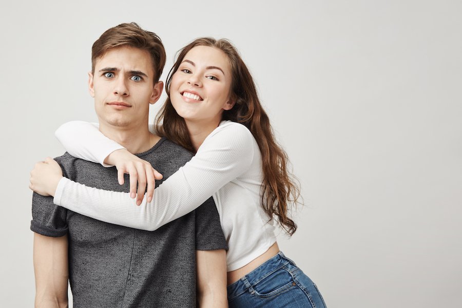 Young teen girl embracing her boyfriend against a blank background