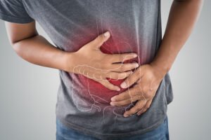 Man suffering from ulcerative colitis clutching his torso in pain