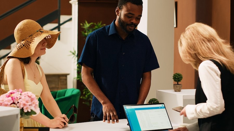 A couple on vacation checking in with a hotel clerk in a tropical location