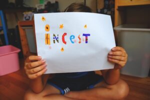 child holding a sheet with marked the word incest
