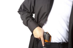 Hombre sacando un arma escondida en la cintura de sus jeans