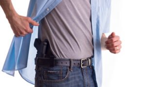 Hombre levantando la camisa revelando un arma en la cintura de sus jeans