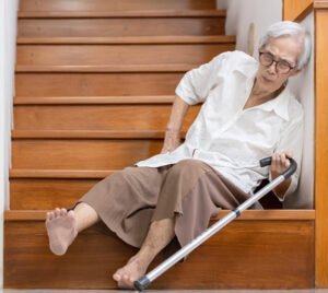 Older woman with a cane lying on a staircase after a fall