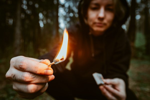 Persona encendiendo una cerilla en un bosque