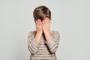 Boy holding hands over eyes following a CRS 18-7-102 violation