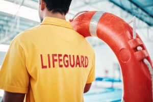 Lifeguard holding a tube by a pool