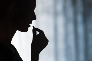 Silhouette of person about to take an opioid pill