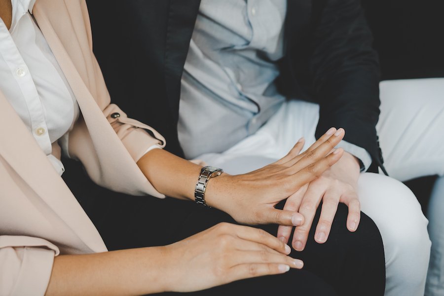 Closeup of man putting his hand on woman's lap against her will